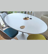 A white tulip dining table with a wooden top and an aluminium base, surrounded by white tulip chairs.