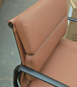 Brown leather chair with black metal frame on a gray floor.