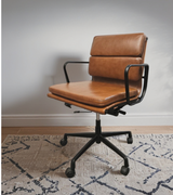 midcentury style low back office chair in tan leather with black swivel base in home office setting.