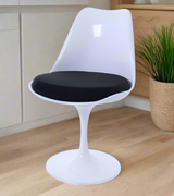 A white tulip style swivel dining chair with a black cushion in a dining room.