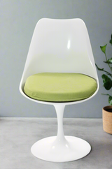 A white tulip style swivel dining chair with a green cushion on a white background.
