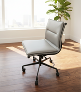 Modern office chair with light grey cushioned seat and black frame in a room with wooden floor and plant.