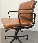 A vintage tan leather office chair with a black frame and five star base, featuring a padded seat cushion and backrest, with no visible wheels.