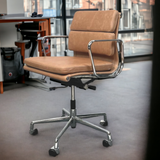 A khaki sand leather office chair with a polished chromed aluminium frame, two padded back cushions, and a padded seat cushion, situated in an office environment.