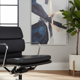 Modern black office chair in a room with abstract art and a plant.